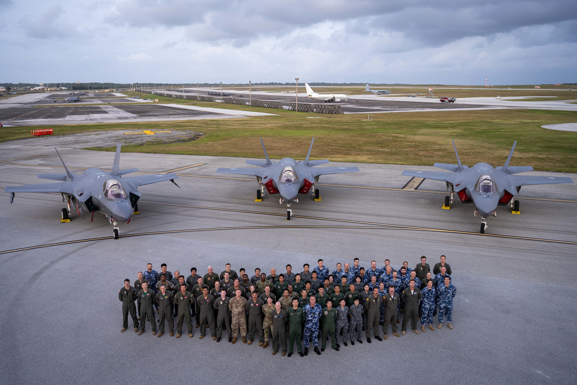 Allies from the United States, Japan and Australia come together for a group photo on the flight-line in front of three F-35A Lightning IIs to celebrate the end of exercise Cope North 2025 at Andersen Air Force Base, Guam, Feb. 21, 2025.