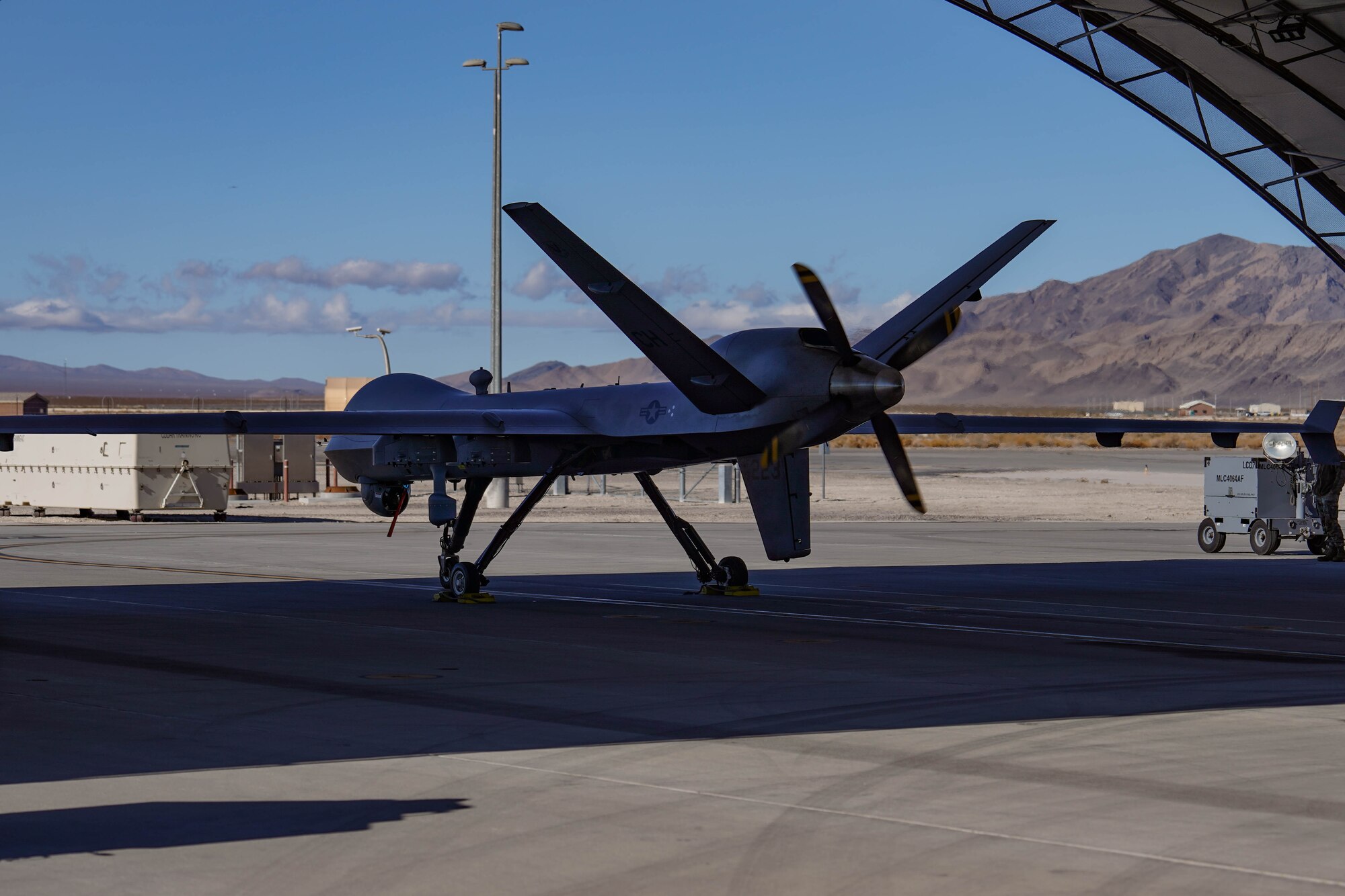 An MQ-9 Reaper sits below a hangar before taxi to the flightline on Creech Air Force Base, Feb. 6, 2025. The MQ-9 is employed primarily as an intelligence-collection asset and secondarily against dynamic execution targets. (U.S. Air Force photo by Staff Sgt. Jake Jacobsen)