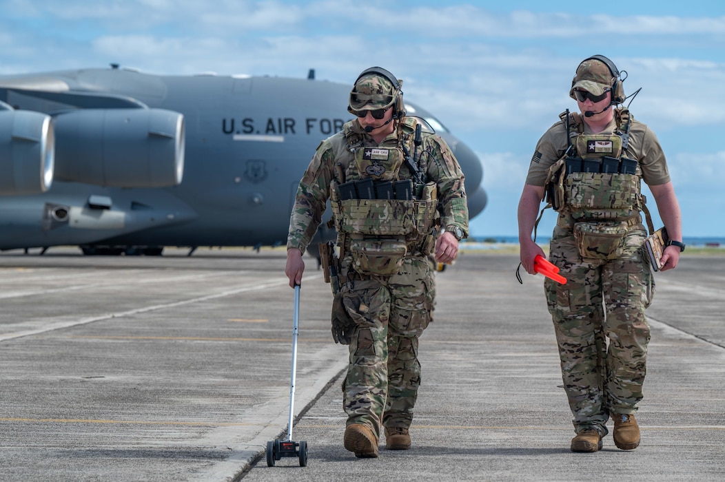 Photo of two Airmen walking on a runway.