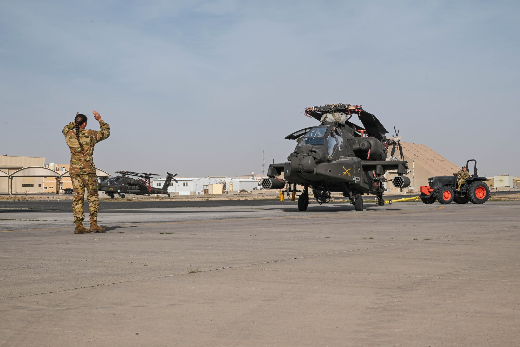 A woman in uniform guides a helicopter being towed.