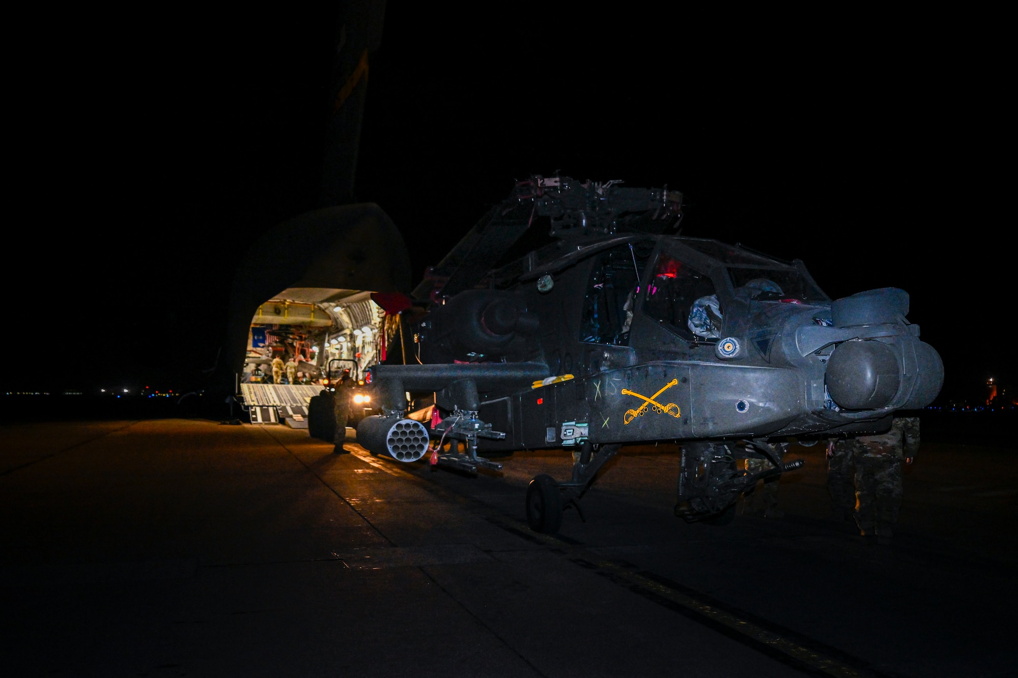 A military helicopter is towed into a plane.
