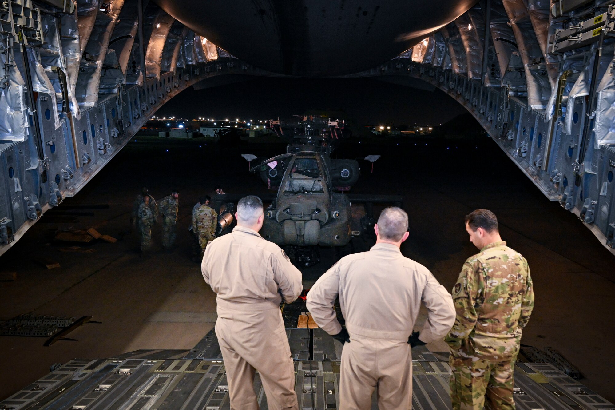 Men in uniform watch a helicopter being towed.