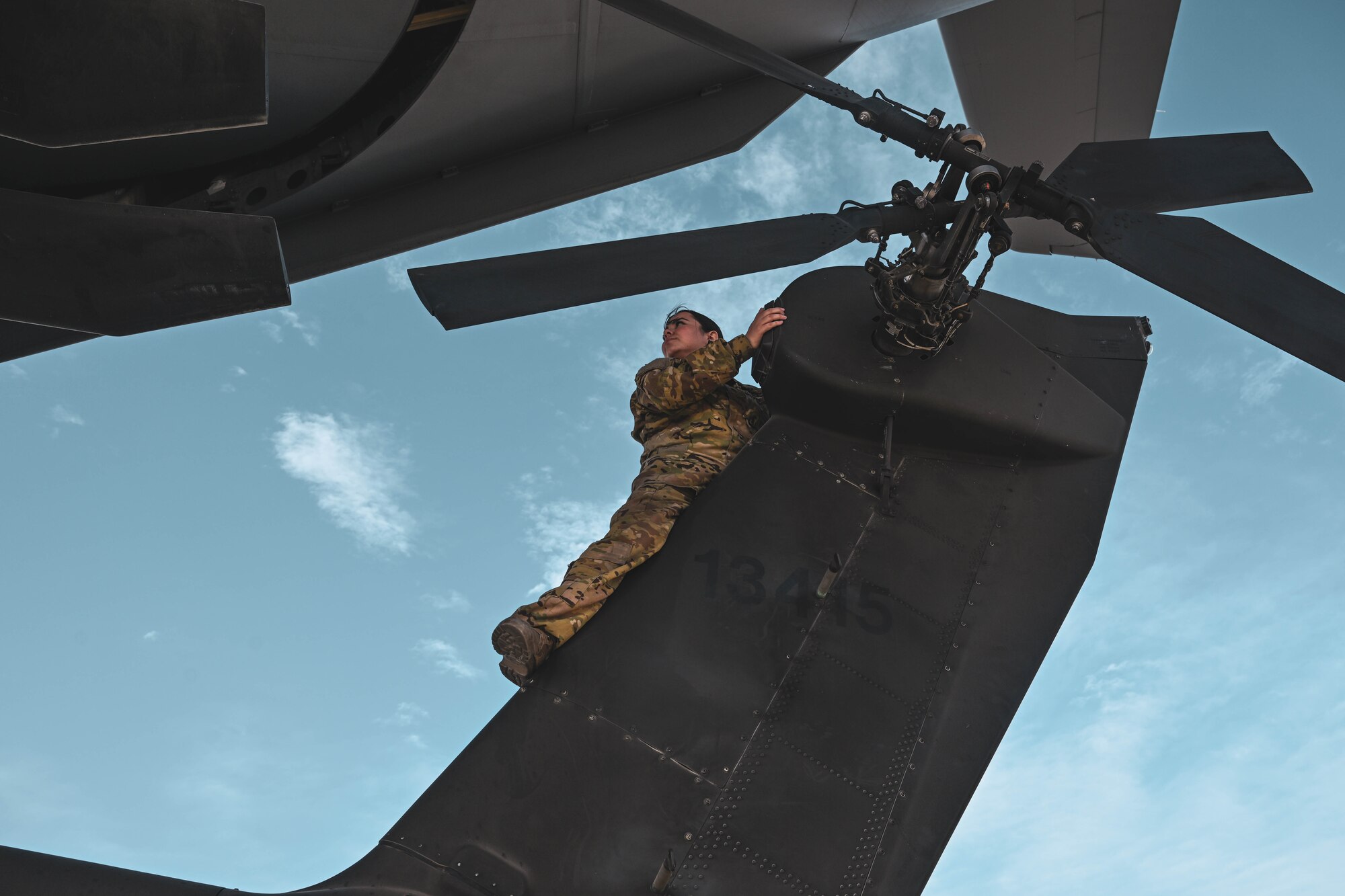 A woman in uniform stands on a helicopter.