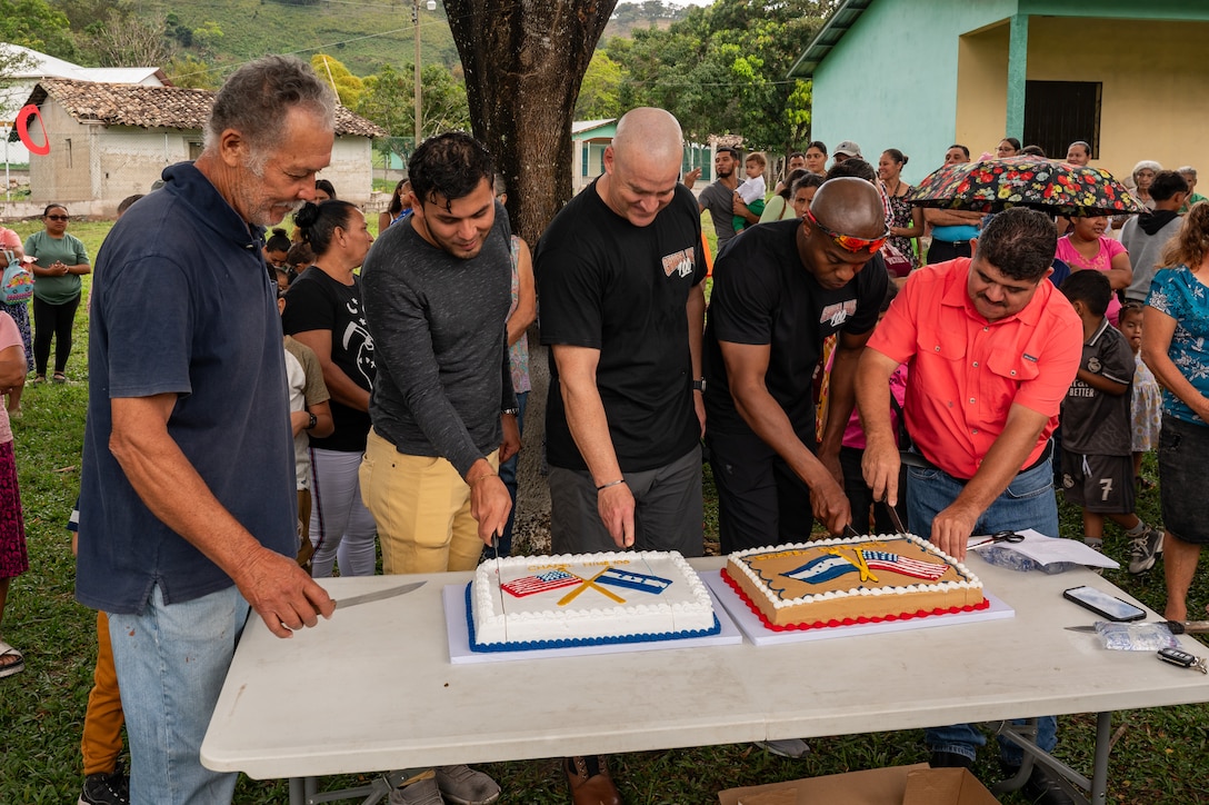 Community leaders from El Llano de la Puerta, alongside U.S. Army Col. Daniel Alder, Joint Task Force- Bravo commander, and Col. William Prince, Army Support Activities commander, cut a cake marking the 100th Chapel Hike Feb. 22. The Chapel Hike, a volunteer program where service members trek to remote villages carrying essential supplies, has become synonymous with JTF-Bravo's commitment to the Honduran people.  (U.S. Air Force photo by Staff Sgt. Tristan Biese)