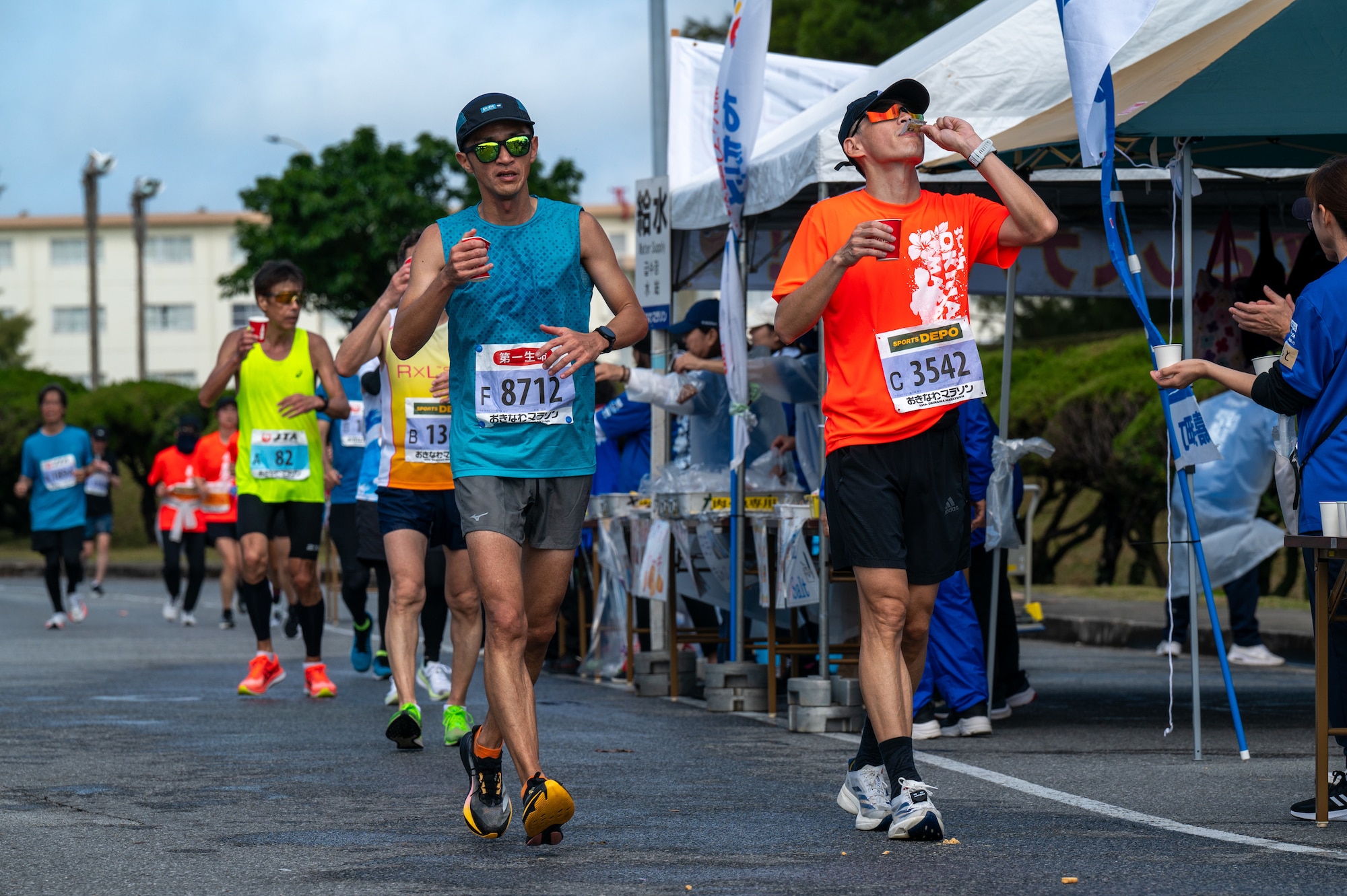 Okinawa Marathon runners taking supplies from a volunteer stand