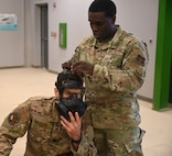 SrA Davionte Shannon fastens Lt Col Christopher Duhon’s mask during CBRN instruction at Joint Base San Antonio-Lackland, Texas on Feb. 5, 2024. By ensuring the proper adjustment of fellow Airmen’s equipment, members prevent the significant dangers associated with improper wear. (US Air Force photo by Alex Dieguez)