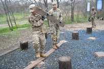 Lt Col Christopher Duhon and Maj Aaron Arntz cross the ‘island hopper’ obstacle using a set of narrow wooden boards at JBSA-Lackland, Texas on Feb. 9, 2024. Variations to this course and others test the dexterity, fitness, and grit of Citizen Airmen for Readiness Airmen Training. (US Air Force photo by Alex Dieguez)