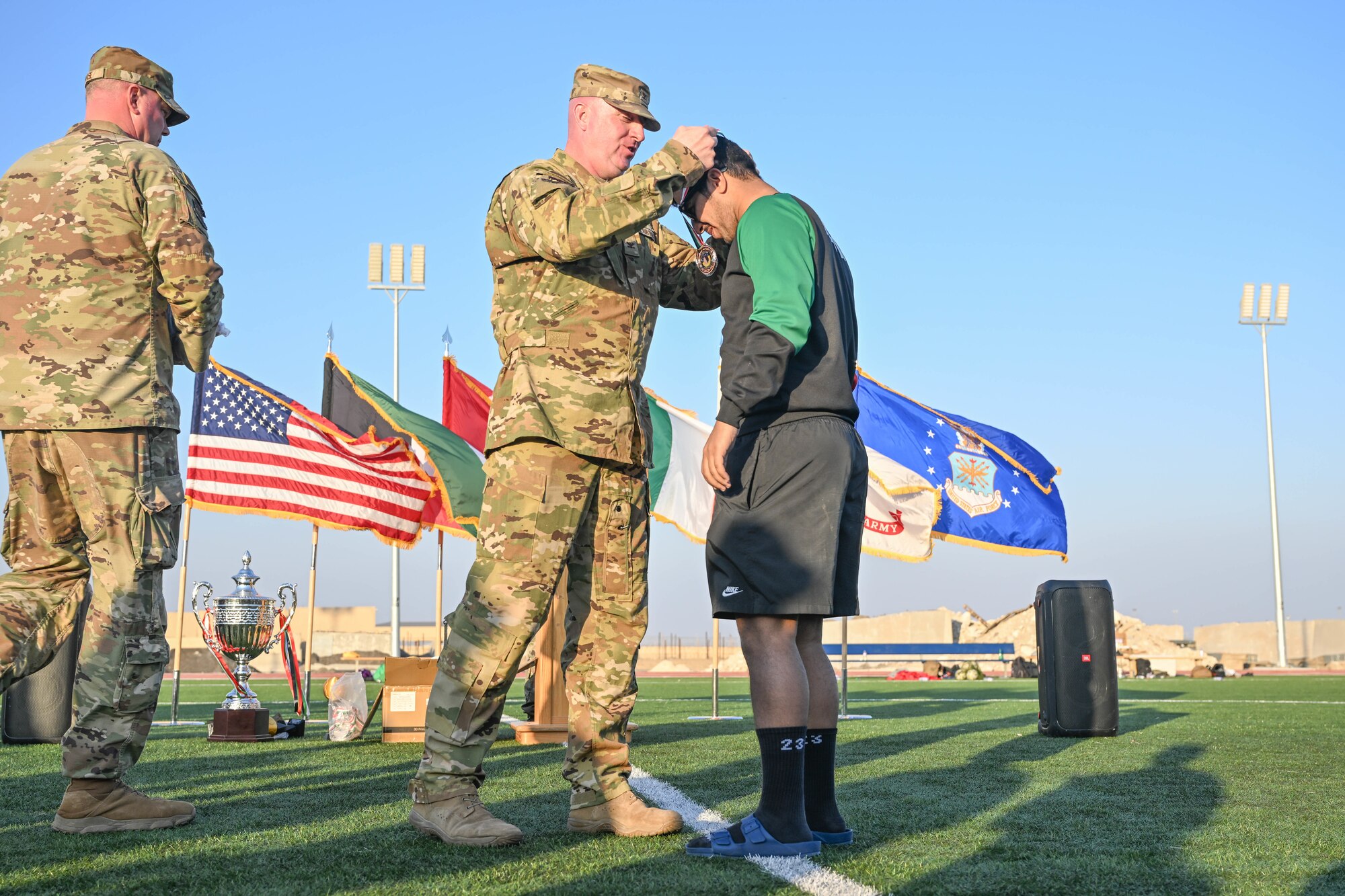 A man in uniform awards a medal to a soccer player.