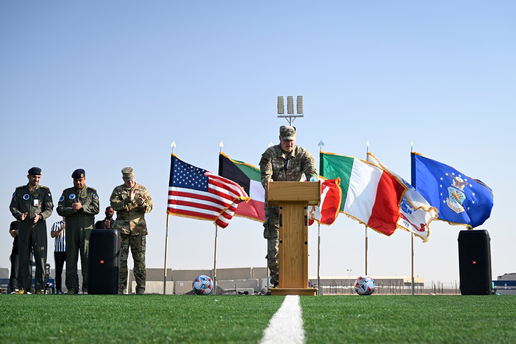 A man in uniform speaks at a podium on a field.