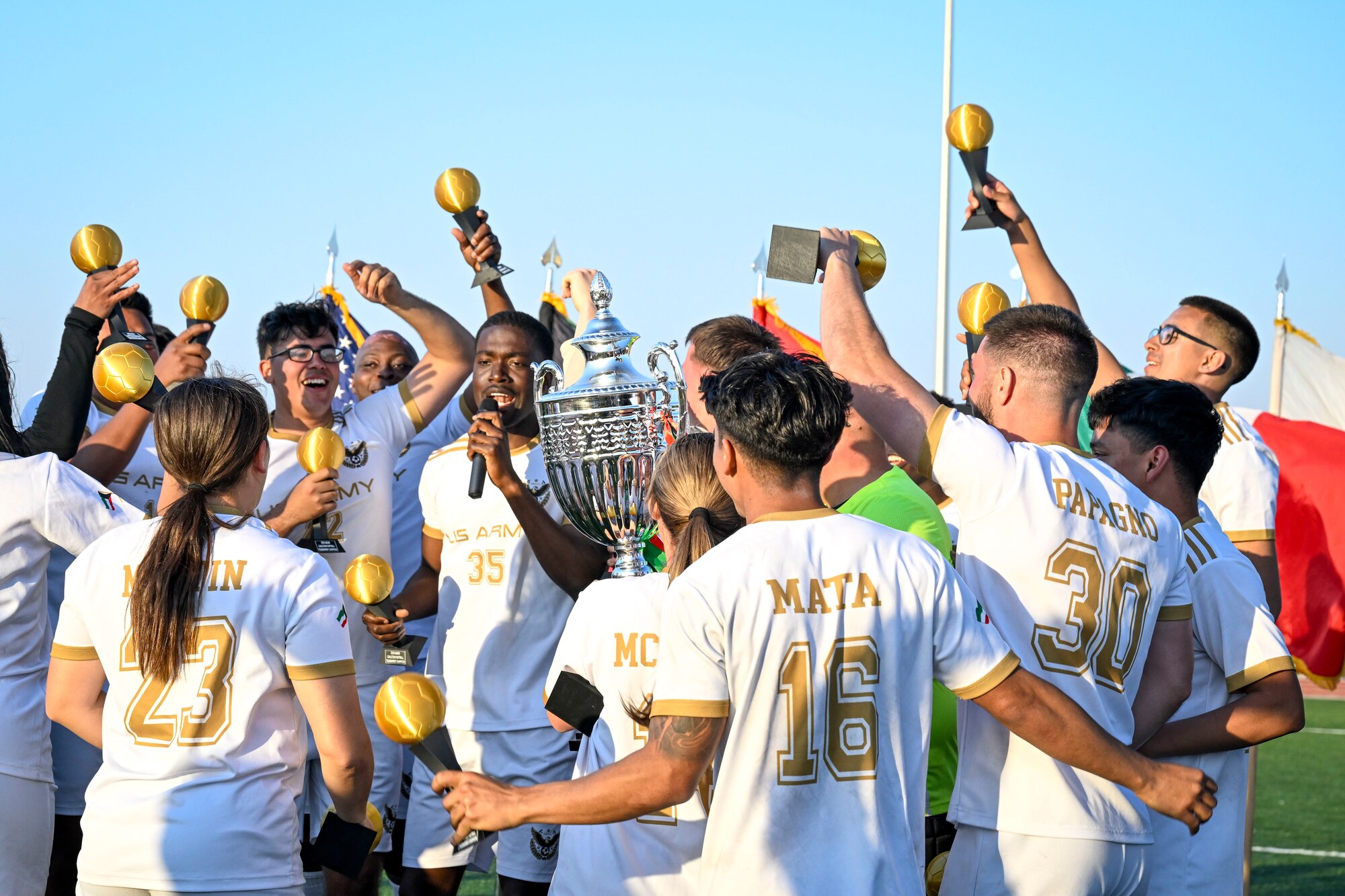 A group of men and women celebrate in soccer jerseys.