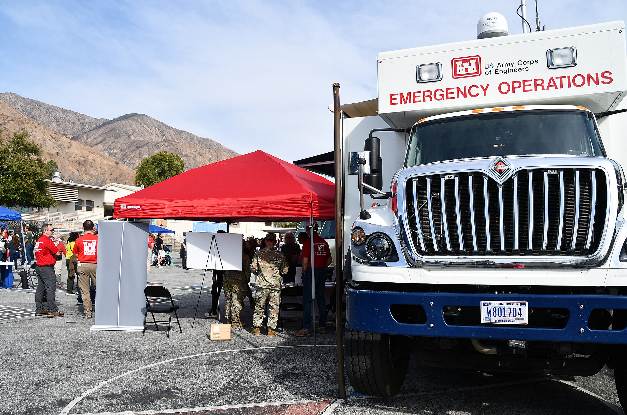 A U.S. Army Corps of Engineers Emergency Operations Vehicle is parked next to a red popup tent where people are working with local community members