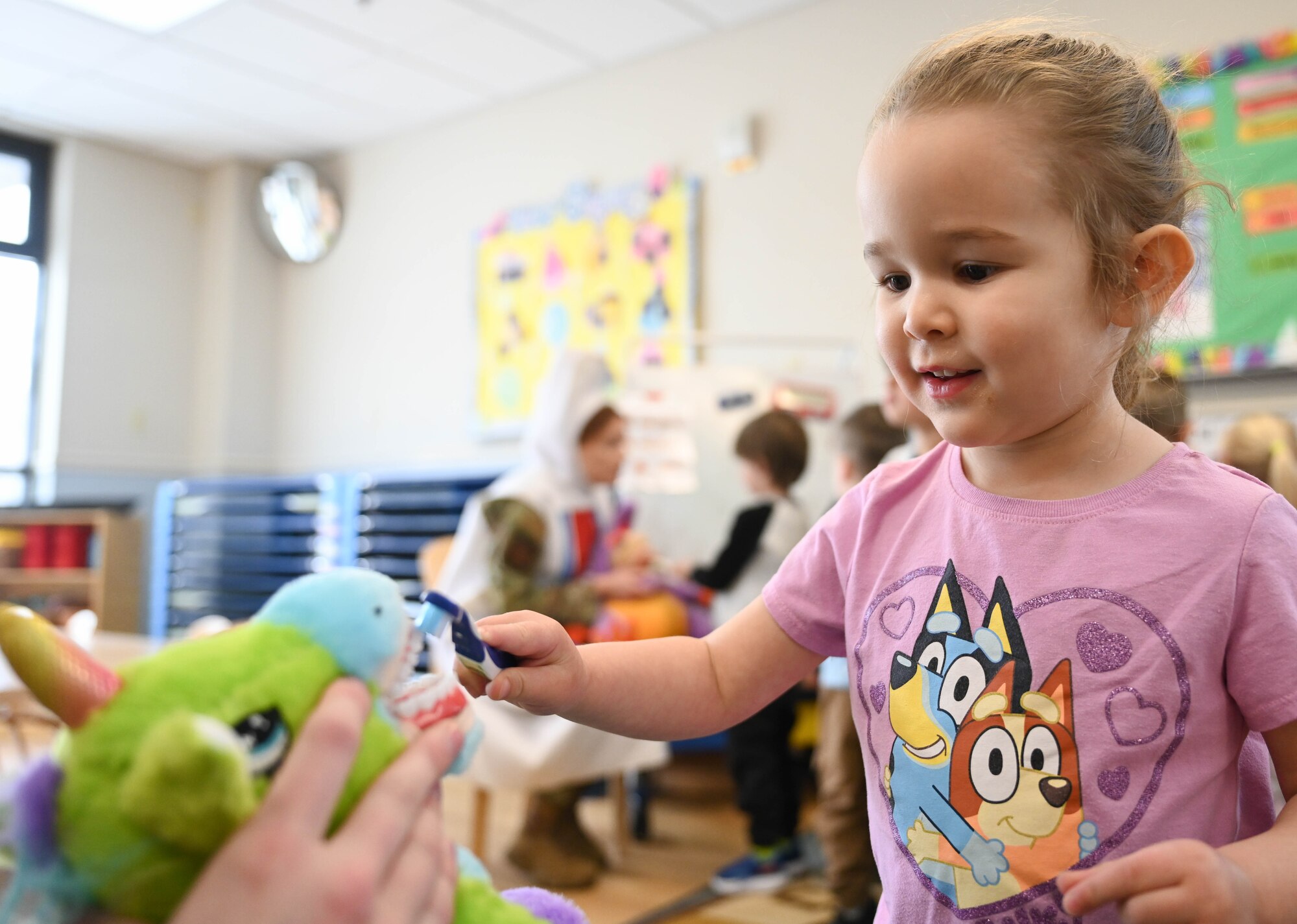 A child brushes the teeth of a stuffed animals as a member of the 21st Dental Squadron.