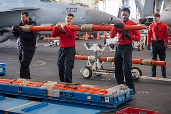 Aviation Ordnanceman, from various squadrons, store aviation litter pods in the hangar bay aboard USS Nimitz (CVN 68) in the Pacific Ocean.