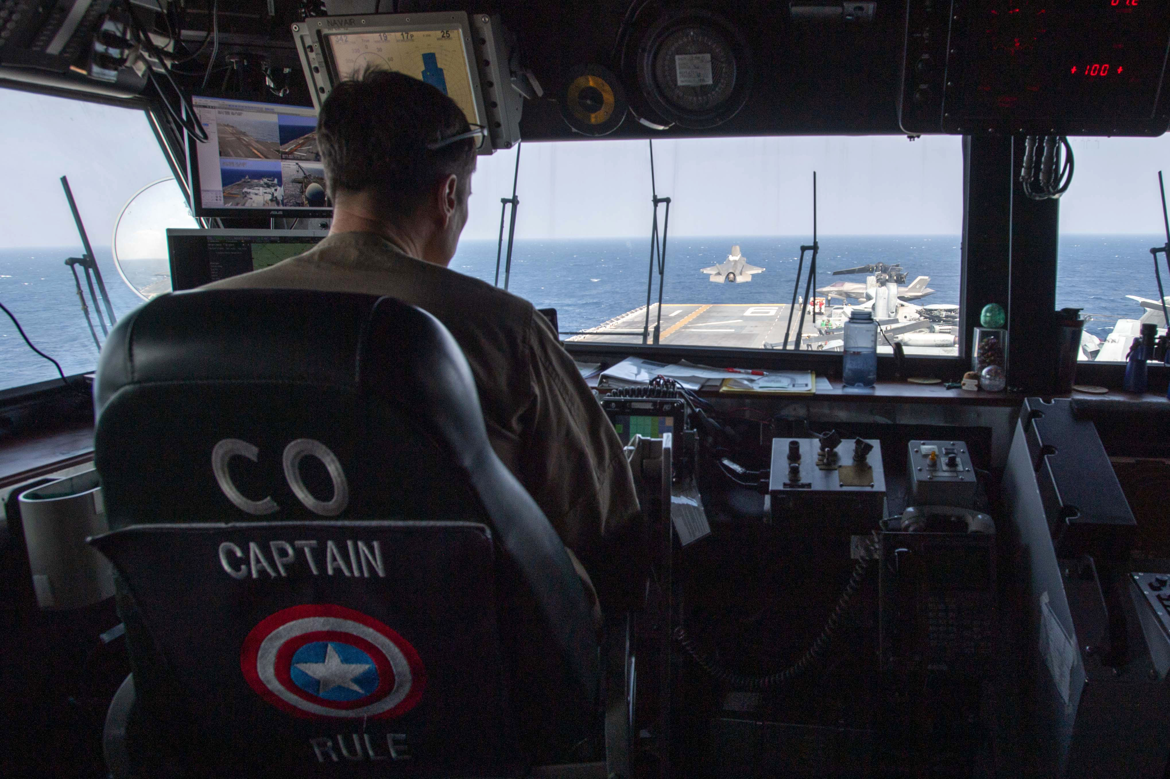 Capt. Ethan Rule, commanding officer of the forward-deployed amphibious assault ship USS America (LHA 6), observes an F-35B Lightning II fighter aircraft from Marine Fighter Attack Squadron (VMFA) 242 take off from the ship's flight deck in the Philippine Sea, Feb. 17, 2025.