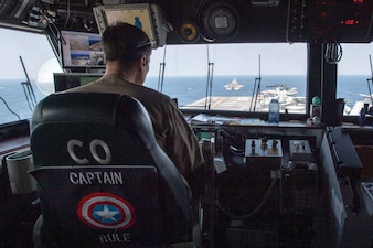 Capt. Ethan Rule, commanding officer of USS America (LHA 6),  observes an F-35B Lightning II fighter aircraft from Marine Fighter Attack Squadron (VMFA) 242 take off from the ship's flight deck in the Philippine Sea.