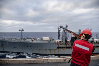 MASN Emma Sanderson fires a shot line from the flight deck of the aircraft carrier USS Nimitz (CVN 68) to USNS Henry J. Kaiser (T-AO 187) during a replenishment in the Pacific Ocean.