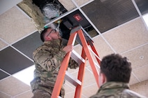 Senior Airman Kyle Corcoran, a heating, ventilation, air conditioning and refrigeration specialist assigned to the 5th Civil Engineer Squadron, inspects an infrared heater at the Combat Arms Training and Maintenance building on Minot Air Force Base, North Dakota, Feb. 18, 2025. Functional airflow is important in the CATM range because downrange airflow prevents firearm debris from blowing back toward Airmen. (U.S. Air Force photo by Senior Airman Kendra A. Ransum)