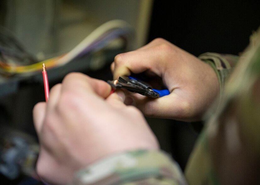 U.S. Air Force Staff Sgt. Micheal Villarreal, a 5th Civil Engineer Squadron heating, ventilation, air conditioning and refrigeration specialist, strips a wire to troubleshoot a furnace at Minot Air Force Base, North Dakota, Feb. 19, 2025. Villarreal responded to a call of a building being cold inside and determined that the furnace needed a new air switch. (U.S. Air Force photo by Senior Airman Kendra A. Ransum)