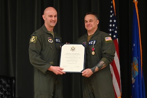 Two men pose with an award.