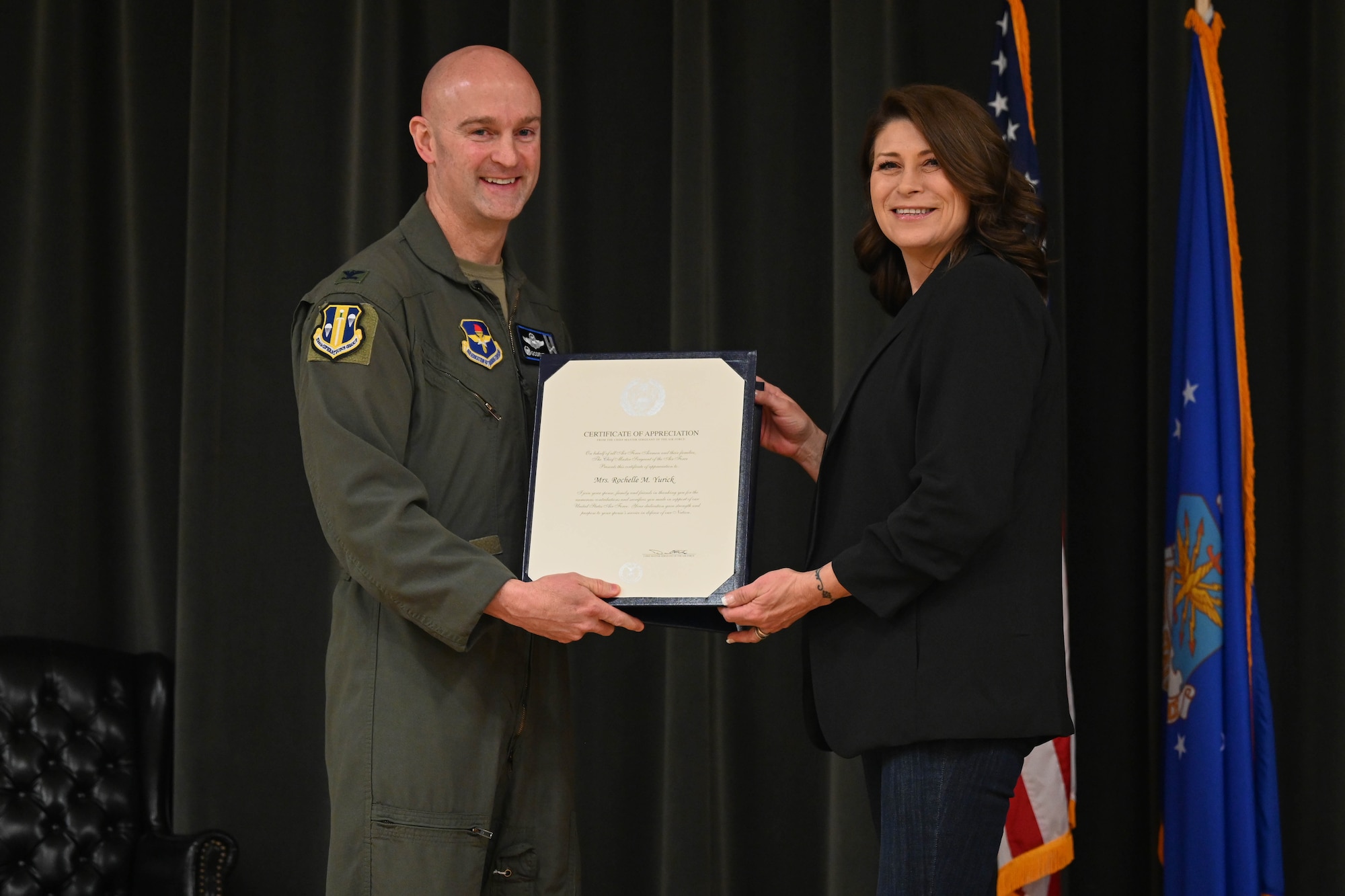 A man and a woman hold an award.