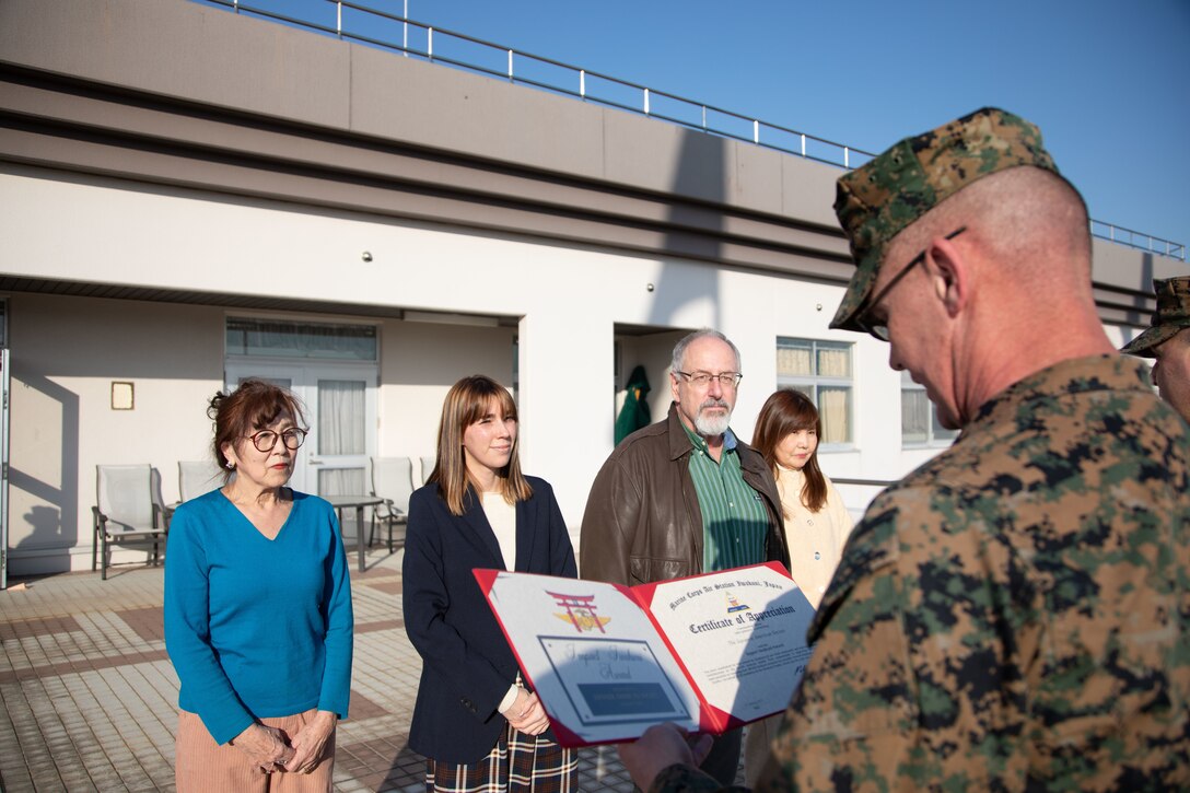 U.S. Marine Corps Sgt. Maj. Jody Armentrout, right, the Marine Corps Air Station Iwakuni sergeant major, and a Texas native, reads the Impact Iwakuni award citation during the February 2025 Impact Iwakuni award ceremony at MCAS Iwakuni, Japan, Feb. 11, 2025. The Impact Iwakuni award is presented monthly to recipients that make a significant positive impact on the community, and the Japanese American Society Iwakuni won the award for its contributions to fostering cross-cultural understanding, unity, and collaboration between the local Japanese community and Americans in Iwakuni. (U.S. Marine Corps photo by Cpl. Colin Thibault)
