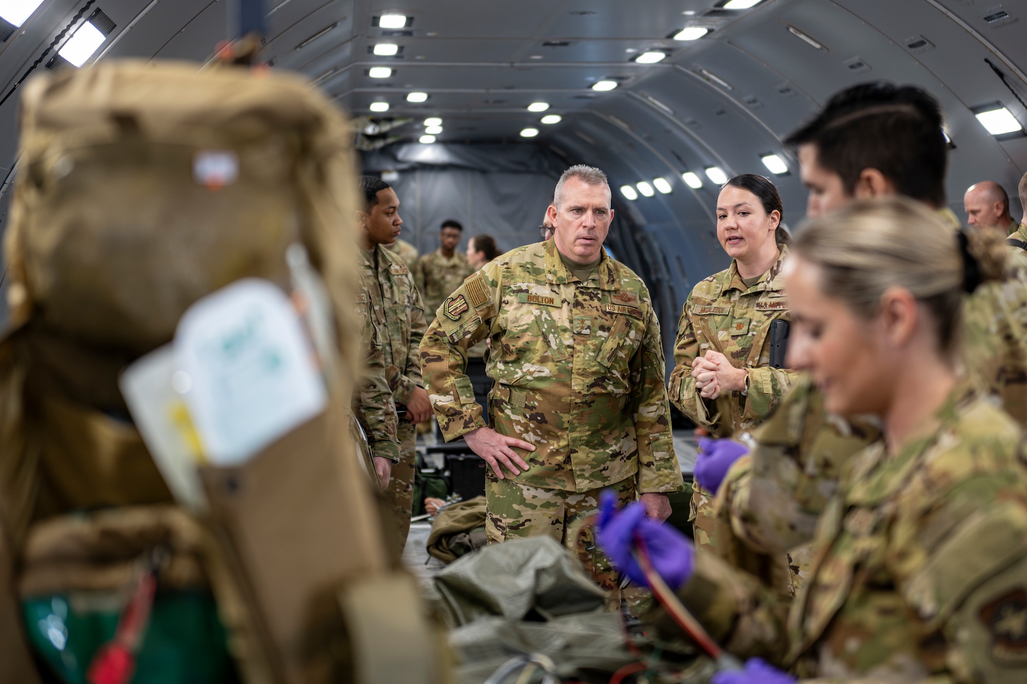 A U.S. Air Force General watches a demonstration on a simulated patient in the back of a plane.