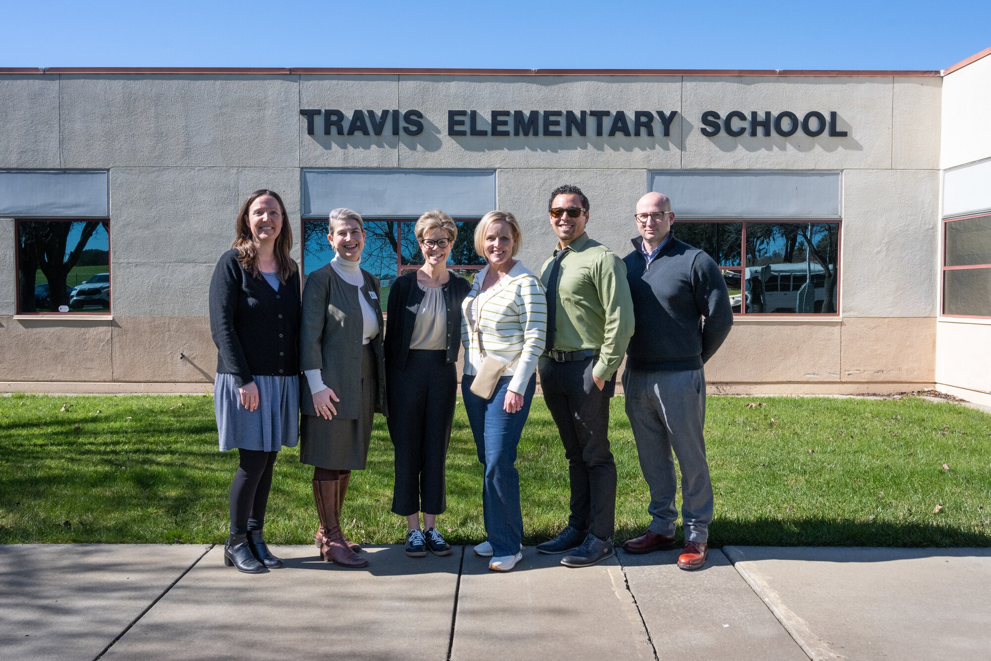 Group stands in front of Travis Elementary School