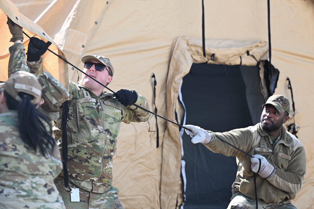 U.S. Air Force 1st Lt. Samuel Houpt, left, 8th Healthcare Operations Squadron medical service core officer, and Staff Sgt. Kemosi Hatten, 8th Medical Group personnel reliability program noncommissioned officer in charge, lift the internal section of a medical tent into position during an expeditionary medical support health response team training at Kunsan Air Base, Republic of Korea.