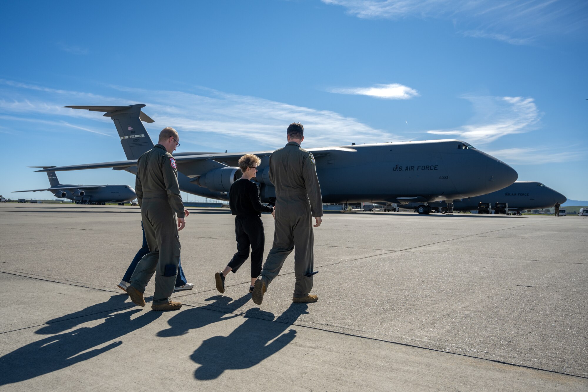 Air Force leadership and a spouse walk on the flight line by a plane.
