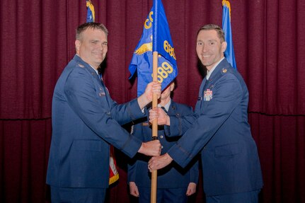 Col. Richard Wallace, 960th Cyberspace Operations Group commander, hands the 689th Network Operations Squadron guidon to Lt. Col. Jason Brosseau, signifying his assumption of command of the 689th NOS, December 6, 2024, at Maxwell Air Force Base-Gunter Annex, Alabama. The 689th NOS is a geographically separated unit of the 960th COG located at Joint Base San Antonio-Chapman Training Annex, Texas. (Courtesy photo from SrA Pratyush Gupta)
