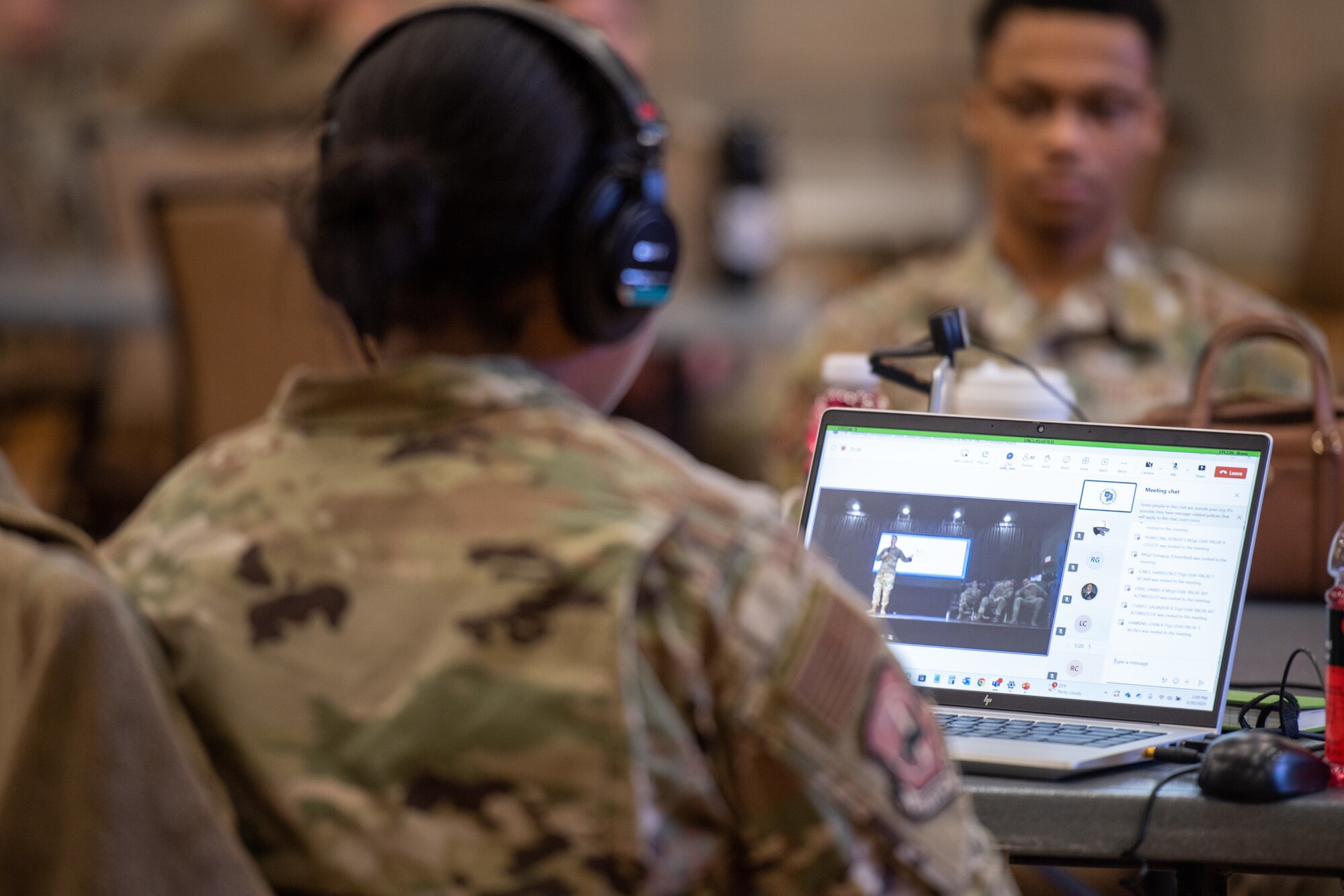 A military members is sitting in front of a laptop.