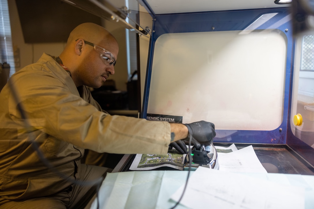 U.S. Marine Corps Staff Sgt. Bryan Bell, a criminal investigator with the 22nd Marine Expeditionary Unit, applies steam to a map to develop latent fingerprints during Marine Air-Ground Task Force (MAGTF) Interoperability Exercise, on Marine Corps Base Camp Lejeune, North Carolina, Feb. 6, 2025. The raid is one of several training events within MAGTF Interoperability, a course conducted by Expeditionary Operations Training Group. This course is designed to evaluate integrated elements of the 22nd MEU across a variety of full mission profiles in a simulated peer threat environment. (U.S. Marine Corps photo by Sgt. Nathan Mitchell)