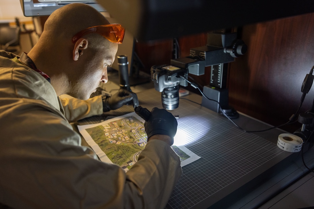 U.S. Marine Corps Staff Sgt. Bryan Bell, a criminal investigator with the 22nd Marine Expeditionary Unit, illuminates a map for fingerprints during Marine Air-Ground Task Force (MAGTF) Interoperability Exercise, on Marine Corps Base Camp Lejeune, North Carolina, Feb. 6, 2025. The raid is one of several training events within MAGTF Interoperability, a course conducted by Expeditionary Operations Training Group. This course is designed to evaluate integrated elements of the 22nd MEU across a variety of full mission profiles in a simulated peer threat environment. (U.S. Marine Corps photo by Sgt. Nathan Mitchell)