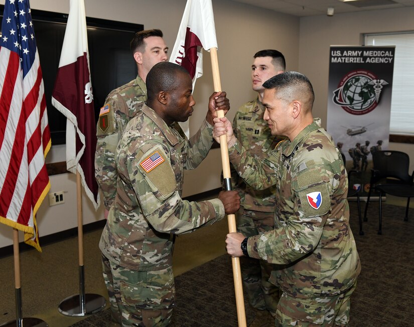 Col. Joselito “Joe” Lim, commander of the U.S. Army Medical Materiel Agency, passes the colors to Capt. Paul Abucher, signifying his trust in him to lead as USAMMA’s new Headquarters and Headquarters Detachment commander during a change of command ceremony Feb. 21 at Fort Detrick, Maryland. The ceremony also recognized outgoing commander Capt. Andrew Whittenbarger.