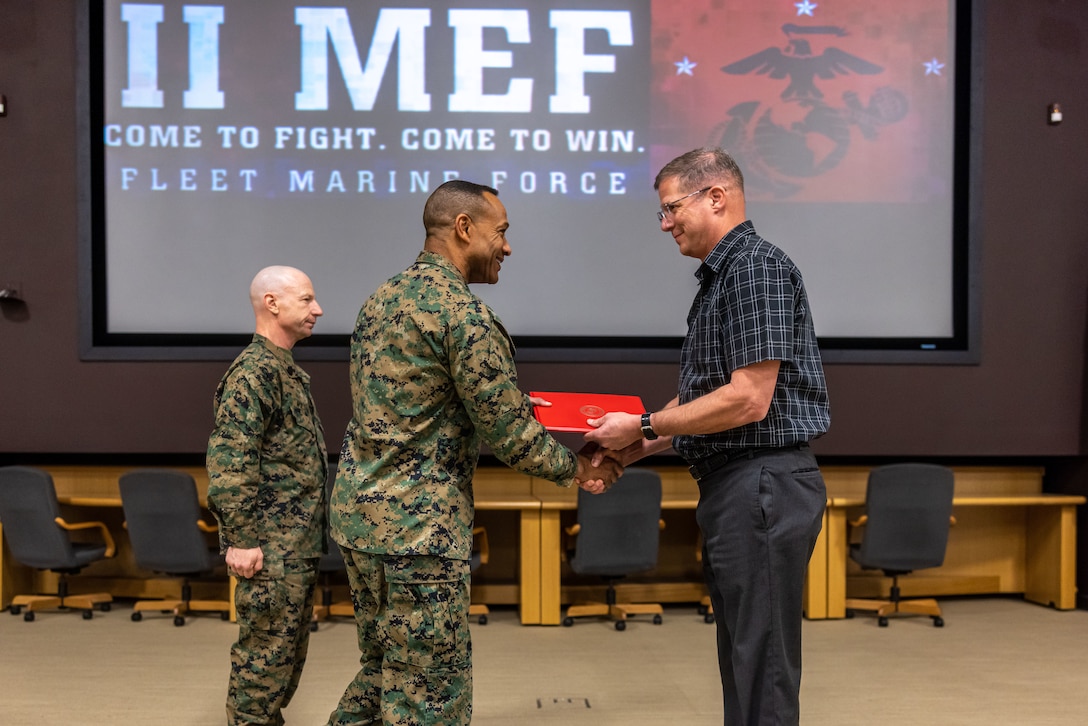 U.S. Marine Corps Lt. Gen. Calvert Worth, the commanding general of II Marine Expeditionary Force (MEF), presents a Navy Civilian Meritorious Service Award to Kevin Johnson, the II MEF Command inspector general chief before a town hall meeting on Marine Corps Base Camp Lejeune, North Carolina, February 21, 2025. Johnson was named the 2024 II MEF Civilian of the Year and given the award for his meritorious service. (U.S. Marine Corps photo by Cpl. Rafael Brambila-Pelayo)