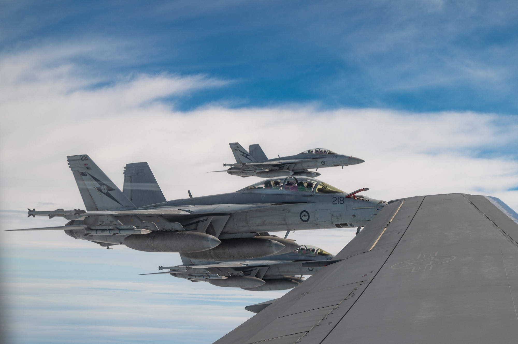 Three F/A-18F Super Hornets, assigned to the Royal Australian Air Force, fly alongside a KC-46 Pegasus while preparing to receive fuel over the Pacific Ocean during exercise Bamboo Eagle 25-1, Feb 12, 2025.
