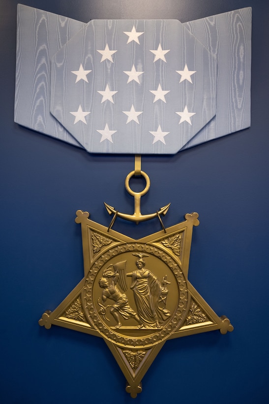 A gold star-shaped medal attached to a blue ribbon rests on a dark blue background.