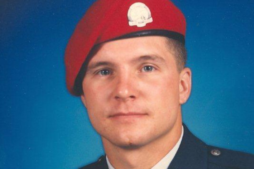 A man in uniform and a red beret poses for a photo.