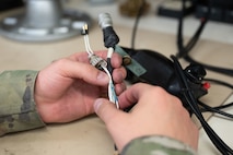 U.S. Air Force Staff Sgt. Shawn Powers, 9th Maintenance Air Force Repair Enhancement Program (AFREP) technician, assesses a splitter cable for damage at Beale Air Force Base, California, Jan. 27, 2025.