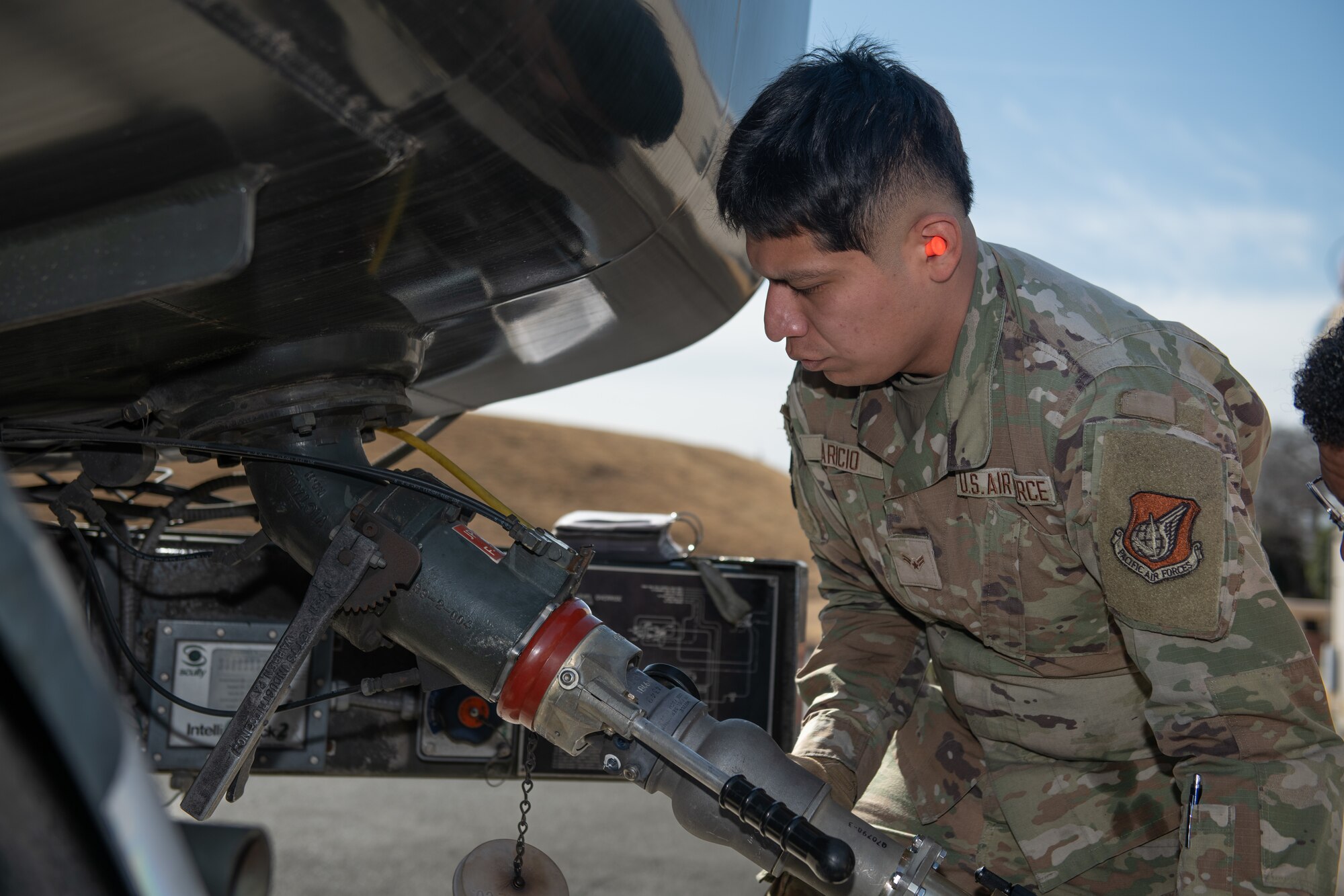 An Airman connects a fuel hose.