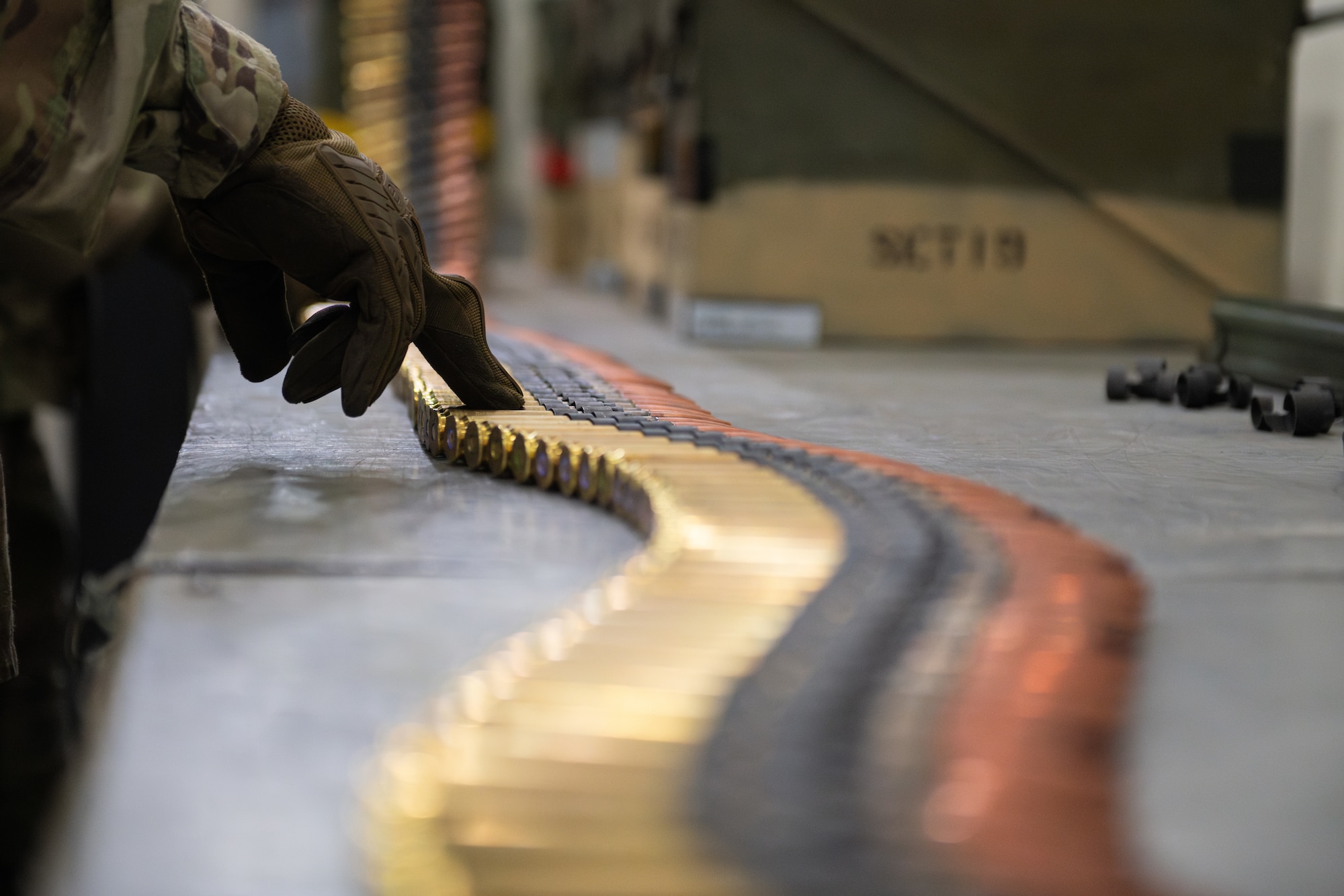 An Airman uses their finger to feel an ammo rounds belt for defects.