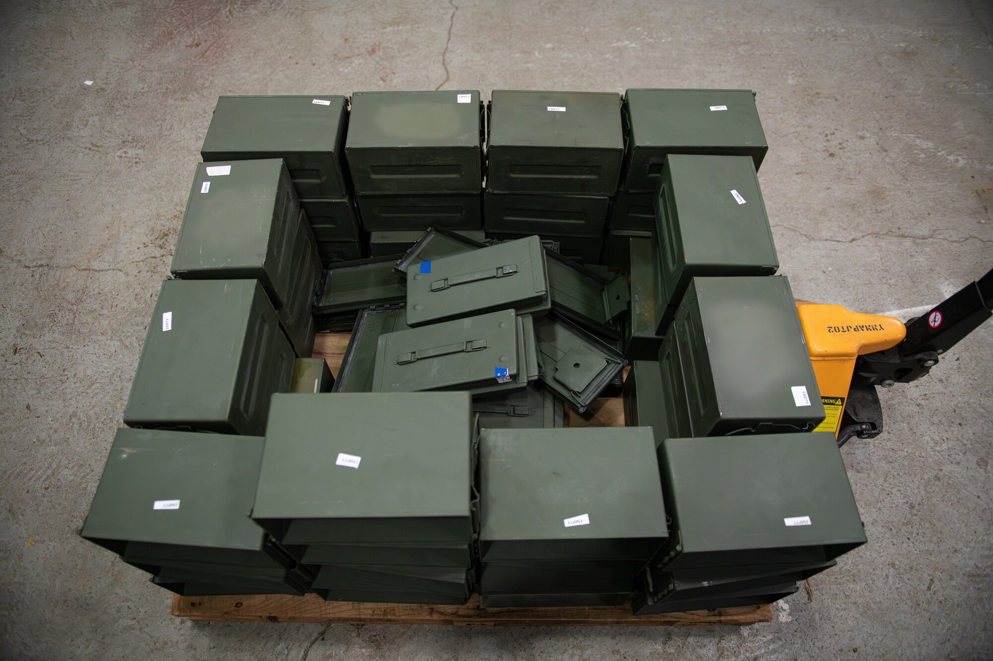 Empty green ammo cartridges are stored on a pallet.