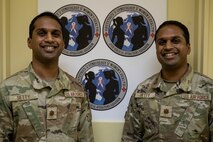 U.S. Air Force Maj. Vinay Setty, left, and Maj. Vijay Setty, 35th Medical Group Gynecologic Surgery and Obstetrics doctors of obstetrics, pose for a photo in front of the OB-GYN logo.