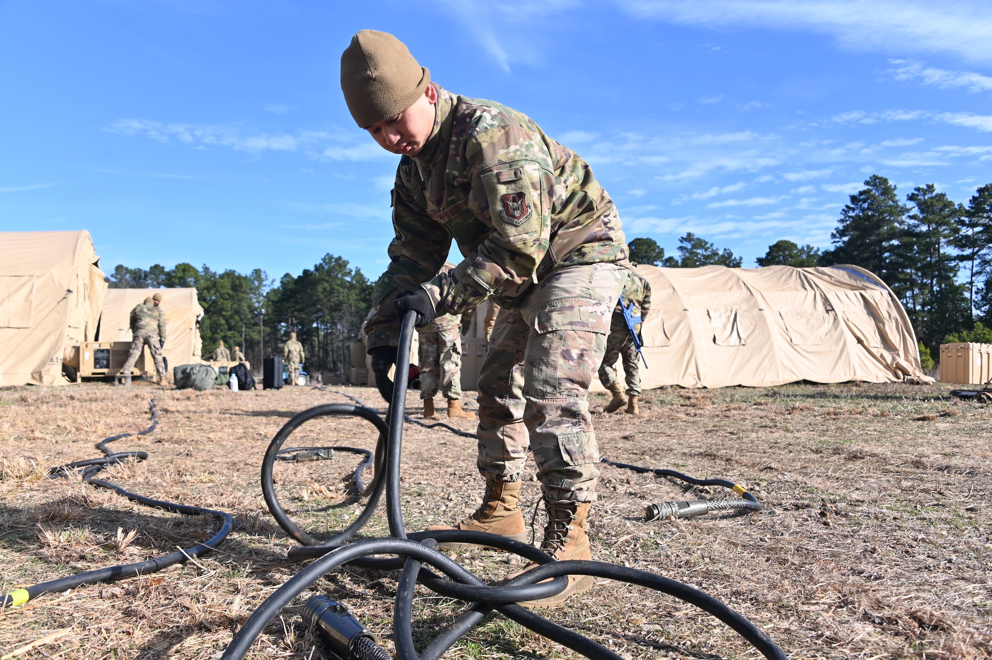 U.S. Air Force Staff Sgt. Thai Nguyen, 307th Civil Engineer Squadron water and fuels maintenance system journeyman, straightens cable to help with getting power to small system shelters February 21, 2025 at Barksdale Air Force Base, Louisiana.