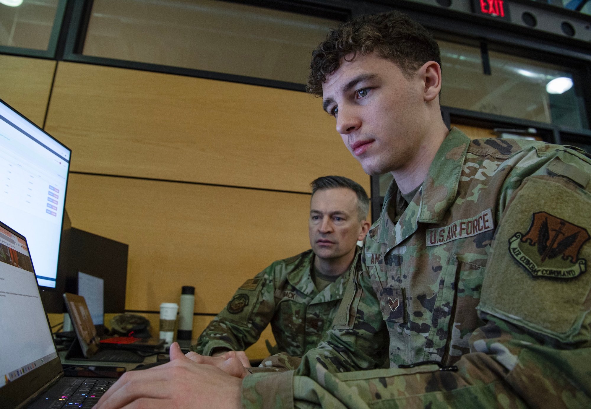 Tow Airmen in uniform type on computers in a large classroom