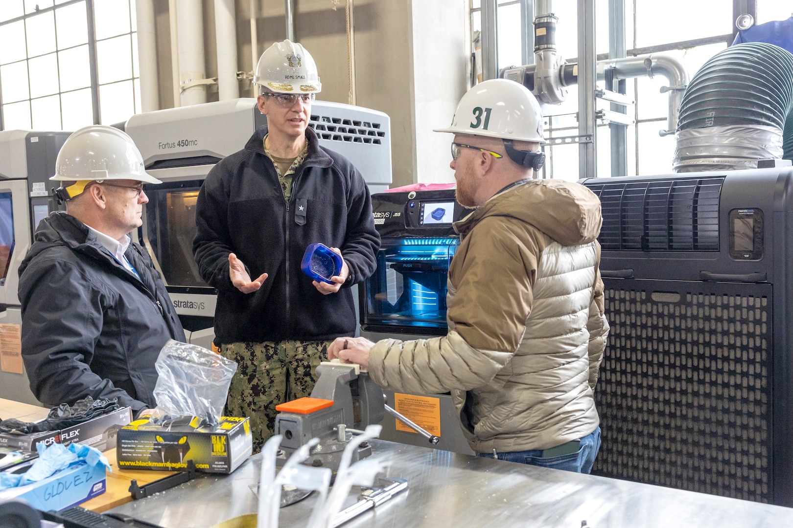 Seth Haskins, additive manufacturing manager, Shop 31, Inside Machinist, briefs Rear Adm. Peter Small Feb. 4, during a tour of Puget Sound Naval Shipyard & Intermediate Maintenance Facility facilities in Bremerton, Washington. (U.S. Navy photo by Wendy Hallmark)