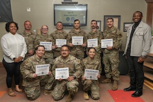 A group of military members pose for a photo with their certificates