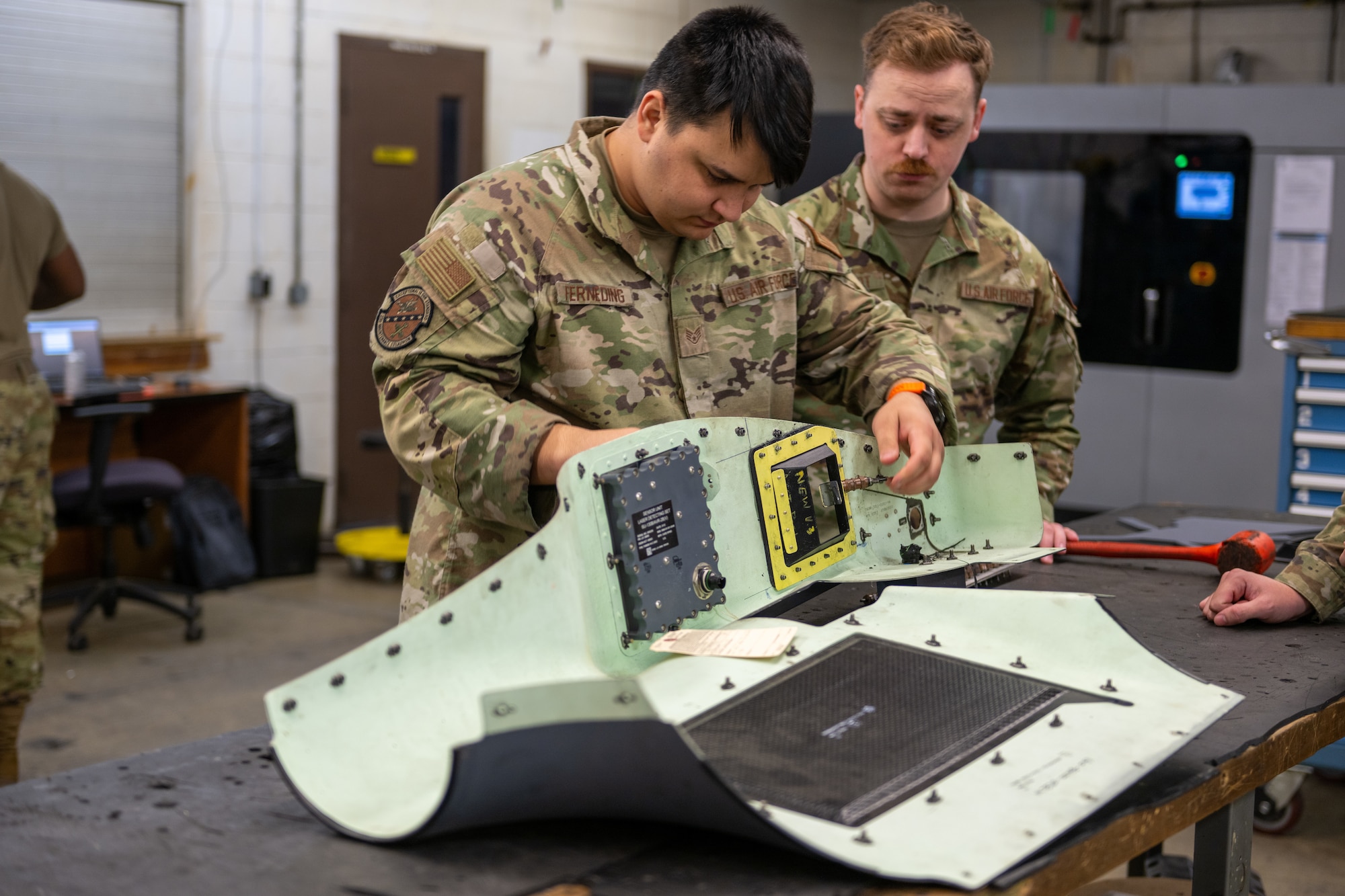Airmen work on a 3D printed part.