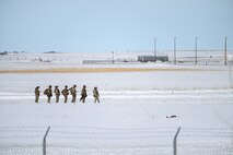 Airmen stand in a line in the snow.