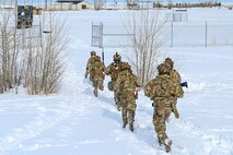 Airmen walk in snow.